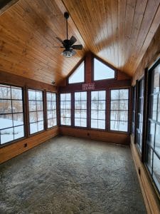 Wide vinyl 3-season sunroom interior with black frames and open design