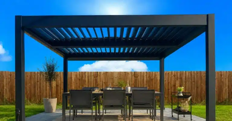Freestanding black louvered pergola shading an outdoor dining table on a sunny patio