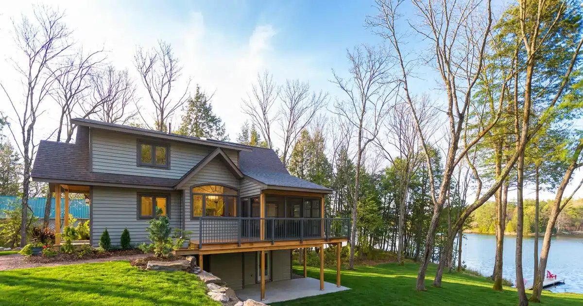 Lakeside cabin with dark aluminum picket railings around an elevated deck