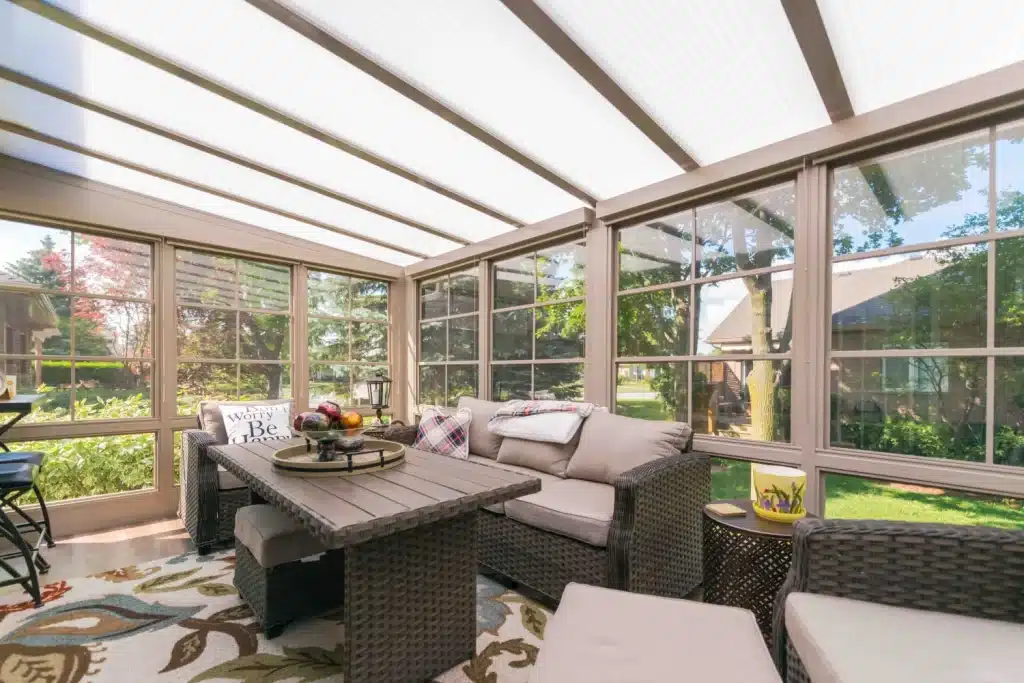 Four-track vinyl windows on adjacent walls of a bright furnished sunroom