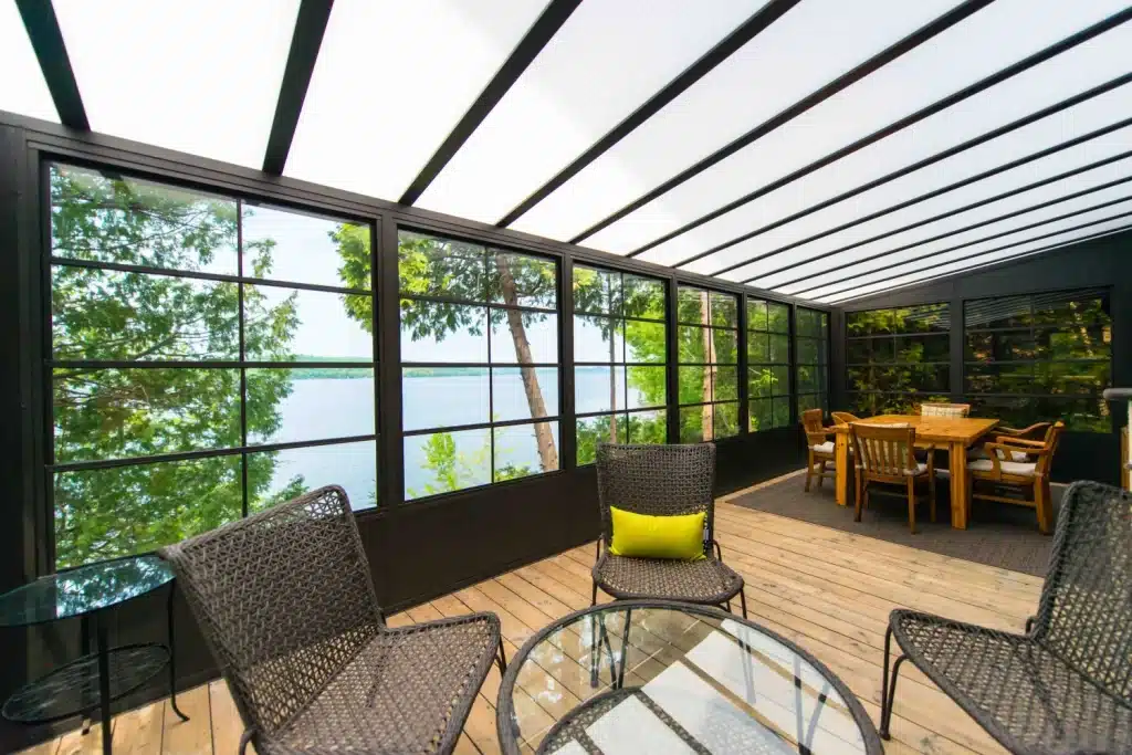Black-framed vinyl sunroom with an acrylic roof overlooking a lake