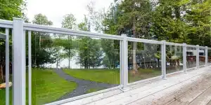 White aluminum glass railing overlooking a wooded lake from a clean deck