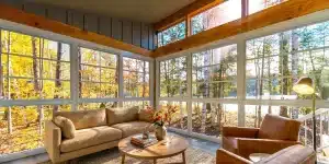 Sunlit vinyl sunroom overlooking golden fall trees and a lake