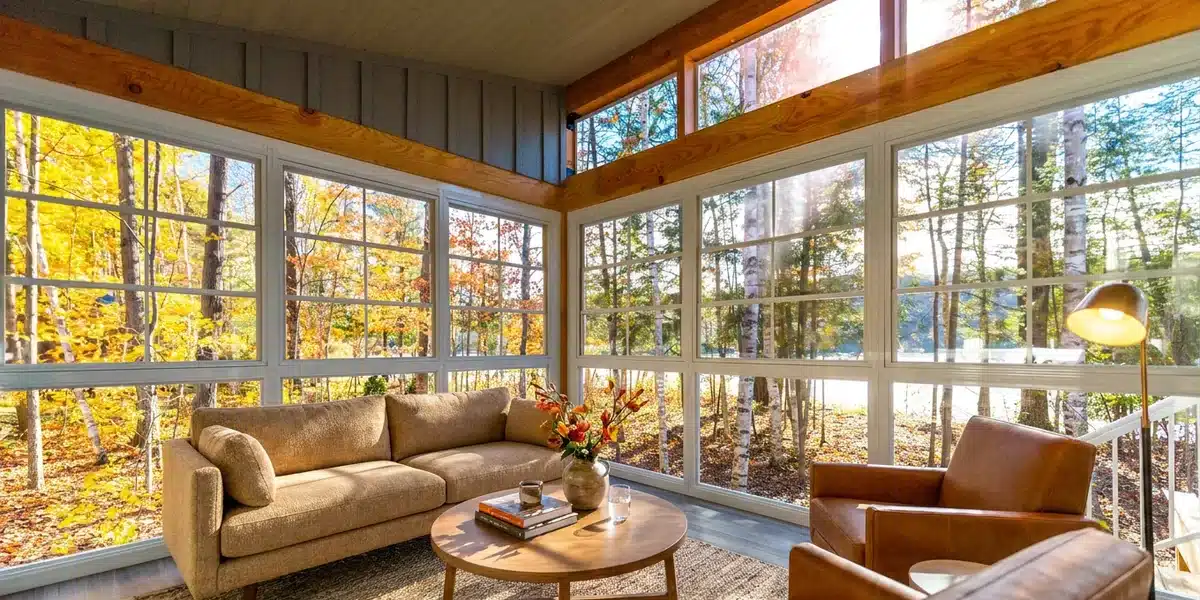 Sunlit vinyl sunroom overlooking golden fall trees and a lake