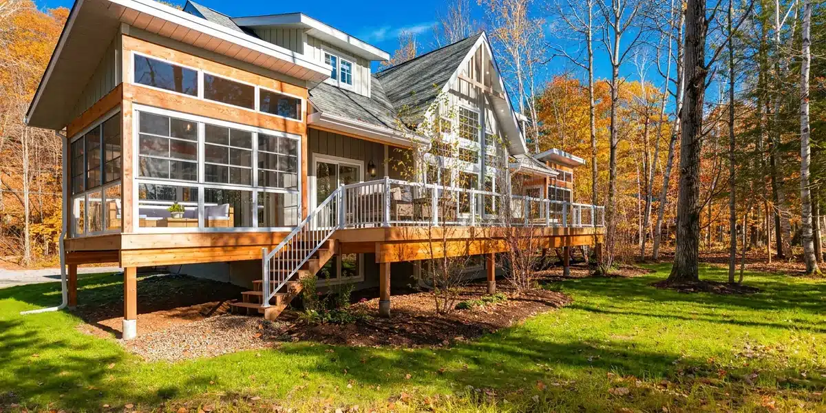Vinyl sunroom attached to a home among orange and gold autumn trees