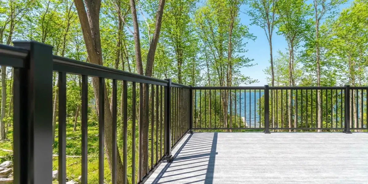 Black aluminum picket railing framing an open view of a lake through trees