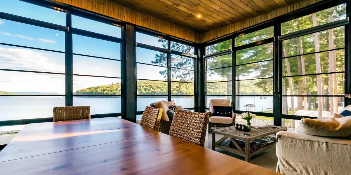 Enclosed lakefront porch with vinyl wall panels, dining table, and water views