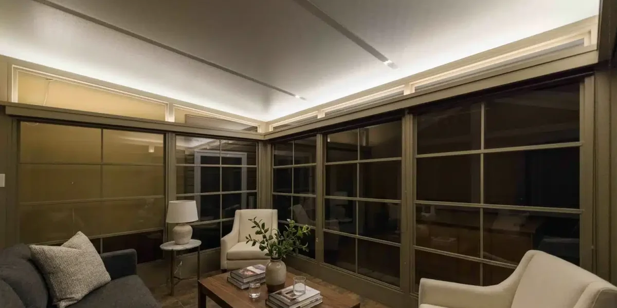 Warmly lit 3-season sunroom with closed vinyl windows after dark